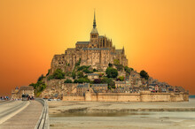 Scenic View Of The Island - Fortress Mont Saint Michel With A Mont-Saint-Michel Abbey Against The Backdrop Of A Dramatic Sunset At Low Tide Of The Atlantic Ocean. Department Manche, Normandy, France