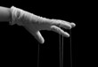 Hand in medical glove with strings on fingers. Fraud, manipulation in medicine, conspiracy theory concept. Black and white. High quality photo