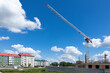 Tower crane with boom raised on construction under blue sky with white clouds