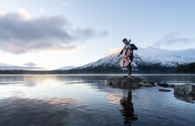 Musician Playing Cello By The Lake With Snow Capped Mountains On The Back