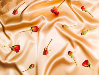 Red roses on gold satin. Concept minimal romance.  Flat lay. Top view.