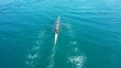 Aerial drone top down video of sport canoe operated by team of young women in emerald clear waters