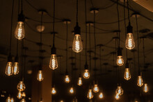 Many Warm Light Incandescent Lamps Attached To The Ceiling On A Wire