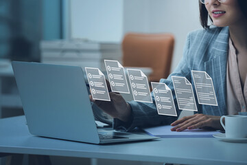 Young secretary with laptop and digital files on virtual screen in office