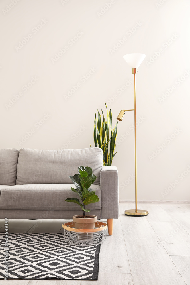 Comfortable sofa and modern lamp near white wall