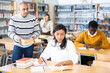 © JackF - Young adult woman working with books, finding information at library