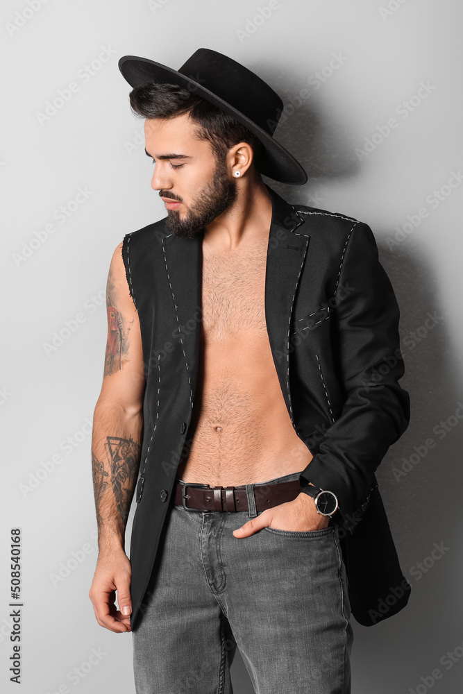 Fashionable man in half-finished jacket looking aside on light background