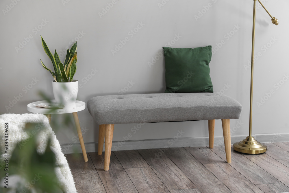 Soft bench with cushion and table near light wall