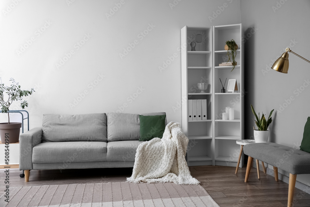 Interior of light living room with soft bench, sofa and shelving unit