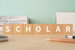 © ELUTAS - 学者・学生のイメージ｜「SCHOLAR」と書かれた積み木が置かれたデスク