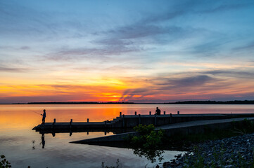 Silhouette of Boy Fishing from Dock at Sunset