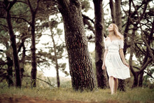 Young Lady Walking In The Woods In A White Dress