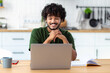 © kucherav - Asian freelancer man using laptop for remote work or watching online training, webinar while sitting at table at home