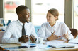 © Mediaphotos - Positive young multi-ethnic business analysts sitting at table with papers and working with financial data while discussing development strategy