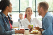 © Mediaphotos - Group of positive carefree young multi-ethnic friends in casual outfits standing at table and having lunch together in fastfood cafe