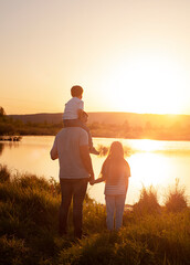 dad and two children are standing by the lake at sunset