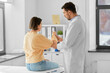 © Syda Productions - medicine, healthcare and people concept - male doctor with clipboard talking to woman showing her sore arm patient at hospital