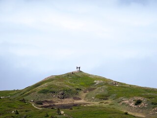 Two people on top of a mountain and sea of clouds in the background