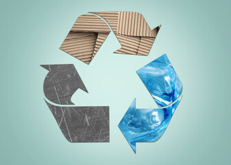 Recycling symbol made of metal, cardboard and plastic bottles on light blue background