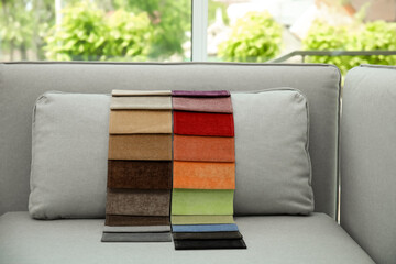 Wall Mural - Catalog of colorful fabric samples on grey sofa indoors