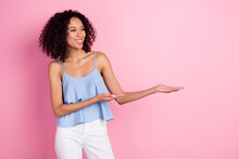 Photo Of Cheerful Pretty Girl Look Arms Hold Empty Space Promotion Isolated On Pink Color Background