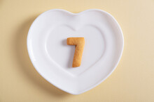 Biscuits Forming Number 7 On The White Plate And Yellow Light Background