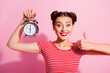 Portrait of cheerful nice girl hold classic clock hand finger show thumb up isolated on pink color background