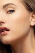 Close up beauty of a half face of a woman with wet radiant skin and big gray eyes. Fashionable natural makeup and wet facial hair. Nude lipstick with kissed lips