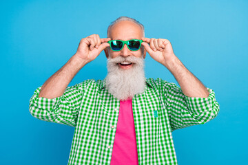 Poster - Photo of satisfied glad aged person hands touch sunglass toothy smile isolated on blue color background