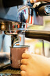 © juanpablo - Close-up of a vintage mug in an espresso machine, with hot coffee coming out of the spout. vertical photo
