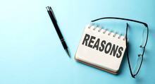 REASONS Text Written On A Notepad On The Blue Background