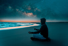 Silhouette Of A Person Meditating Alone On The Beach At Night With The Milky Way In The Background