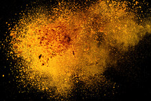 Explosion, Splashes Of Turmeric On A Black Background. India Seasoning. The Orange Powder Of The Turmeric Root. Explosion Of Powder