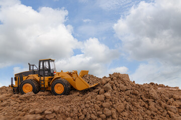 Wall Mural - Wheel loader are digging the soil in the construction site on sky background ,with white fluffy cloud