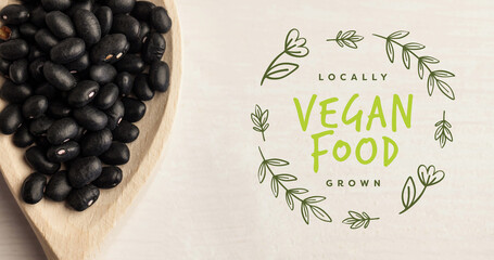 Image of vegan food text in green over fresh organic black beans on wooden boards