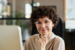 © pressmaster - Portrait of young office worker in eyeglasses smiling at camera while working on computer at office