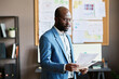 © pressmaster - African businessman in eyeglasses examining business documents while standing at office
