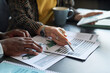 © pressmaster - Close-up of businesswoman pointing at report with graphs and discussing it with her partner at meeting