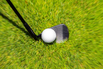 Wall Mural - Closeup of hitting golf ball with golf iron club golf course wih motion blur effect