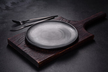 An empty plate with a knife, fork or spoon with a wooden cutting board