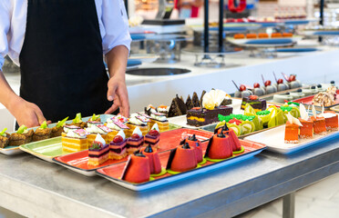 Wall Mural - Waiter decorating pastries and cakes in the hotel bar