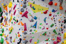 Street Artificial Rock Climbing Wall Close-up View Various Colored Grips. Colorful Footholds For Training. White Climbing Wall Background