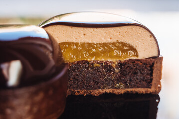 Modern tropical mini mousse covered with mirror glaze. Mini chocolate mousse cake in cut on a blue background. Modern European dessert