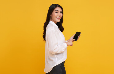 Poster - Happy young Asian woman showing at blank screen mobile phone isolated over yellow background.