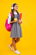 © Olena - Back to school. Teenage school girl with bag hold apple and book, ready to learn. School child on isolated yellow studio background. Happy face, positive and smiling emotions of teenager girl.