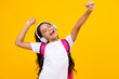 Amazed child singing. Amazed teen girl. School teenager child girl in headphones with school backpack. Teenager student, isolated background. Learning music. Excited expression, school leisure.