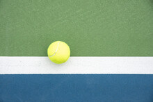 Top View Of A Tennis Ball Hitting Outside The Line Of The Doubles Sideline On A Court.