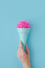 Woman Hand Hold Pink Paper Ice Cream Scoop With Ice Cream Plastic Cone On Bright Blue Background. Minimal Summer Concept. Micro Plastic In Food. Recycling.