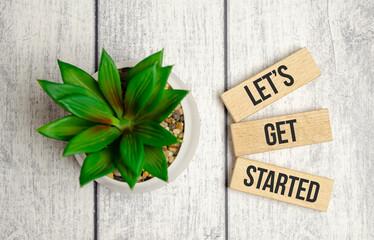 let is got started words on wooden blocks and green plant