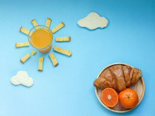 Creative breakfast idea, sunrise morning blue sky with cloud meal, Orange juice, crispy bread butter sugar, cloudy white bread, croissant and orange fruit. Wake up in brighter day with vitin C.